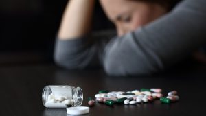 Depressed woman beside a lot of pills