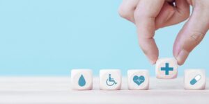 Hand chooses a emoticon icons healthcare medical symbol on wooden block , Healthcare and medical Insurance concept