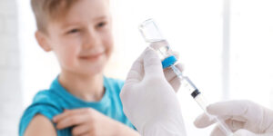 Doctor filling syringe with medicine and child on background. Vaccination day
