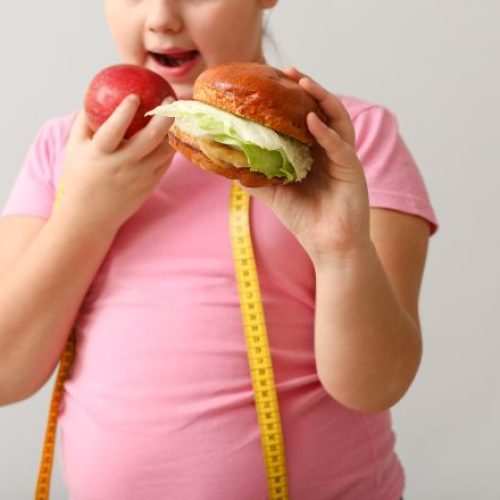 Overweight girl with healthy and unhealthy food on light background
